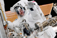Tom Jones grips a handrail on the Node 1 module as he transfers tools on the International Space Station during STS-98. At his left hip is a portable articulating foot restraint, used to provide stability during EVA assembly work. Above him, the ISS solar arrays stretch 240 feet from tip to tip. NASA photo by Marsha Ivins.
