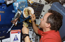 Astronaut Thomas D. Jones assembling a breakfast burrito during STS-80.  He later went on to assemble the Destiny laboratory to ISS-Alpha during STS-98, during several spacewalks.  Note that Tom is having decaf with his breakfast.